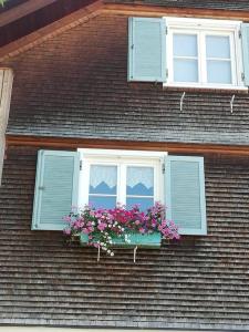 una finestra su una casa con fiori in un box finestra di Gemütliche Wohnung in Einfamilienhaus ad Alberschwende
