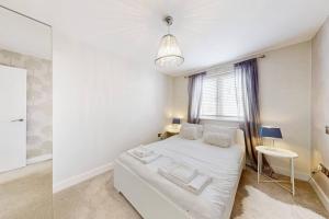 - une chambre blanche avec un lit et une fenêtre dans l'établissement Stylish 2bed2bath flat 4min from tube station, à Londres