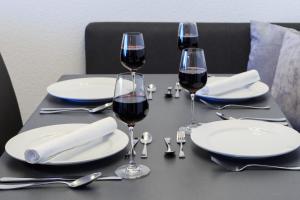 a table with two glasses of red wine and silverware at Relax-Apartment mit Indoor-Pool, Sauna, Massagesessel und Netflix in Schonach