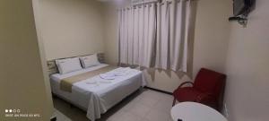 Pousada Cardoso في Ipiaú: غرفة نوم صغيرة بسرير وكرسي احمر