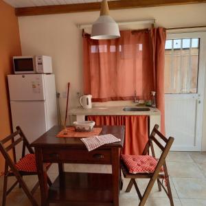 a small kitchen with a table and a refrigerator at Monoambiente en Colonia in Colonia del Sacramento