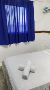 Hotel Rumbo al Sol في بلاياس: منشفتان فوق سرير وستارة زرقاء