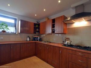 Una cocina con armarios de madera y un fregadero y una ventana. en Szymkówka, en Nowa Biała