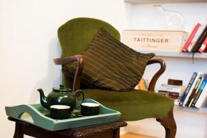 a green chair with a tray of tea cups on a table at Characterful Abode with FREE parking. in Liverpool