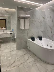 Baño blanco con bañera y lavamanos en Temandra Hotel en Yeda