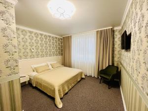 una camera d'albergo con letto e sedia di Готель Лаванда a Chmel'nyc'kyj