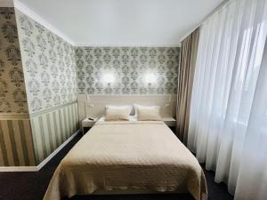 una piccola camera con un letto e due finestre di Готель Лаванда a Chmel'nyc'kyj