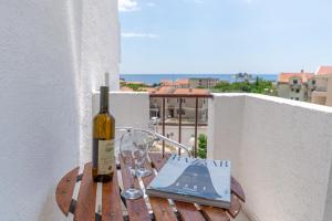 eine Flasche Wein und ein Buch auf dem Tisch auf dem Balkon in der Unterkunft Apartments Vjera Petrovac in Petrovac na Moru