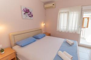 sypialnia z łóżkiem z niebieskimi poduszkami i oknem w obiekcie Apartments Vjera Petrovac w Petrovacu na Moru