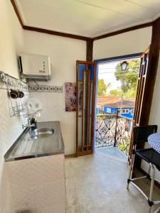 a kitchen with a sink and a door to a balcony at Vila Pequeá Ilhabela in Ilhabela