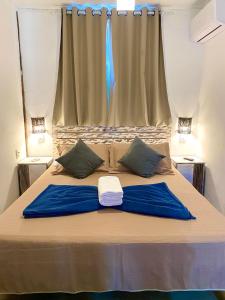 a bed with two blue pillows and a window at Vila Pequeá Ilhabela in Ilhabela