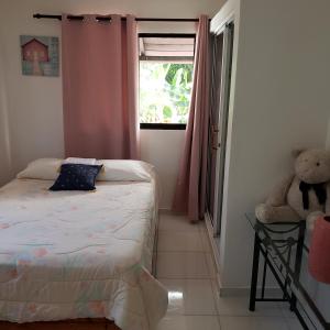 a bedroom with a bed and a teddy bear next to a window at Lovely location , right downtown Puerto Plata in San Felipe de Puerto Plata