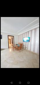 a room with a table and chairs and a television at Résidence jnane California in Casablanca