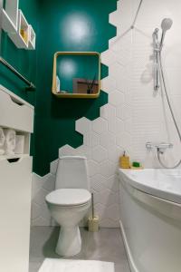 a bathroom with a toilet and a green wall at Brassy apartment in Rīga