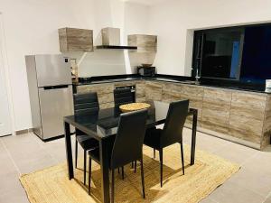 a kitchen with a black table and black chairs at Tahiti Moetama Cosy Lodge - VILLA ITI in Punaauia