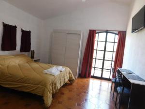 1 dormitorio con cama, escritorio y ventana en Filipao Aparts en Santa Rosa de Calamuchita