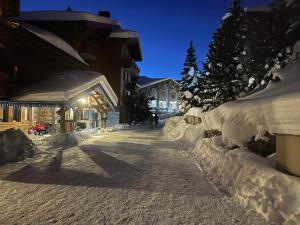 a street covered in snow at night at Appartement ski aux pieds dans résidence premium piscine, sauna hamam in Les Menuires