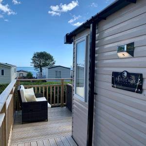a deck with a chair and a sign on a building at Lydstep Beach BayView 3-Bedroom Holiday Home in Tenby