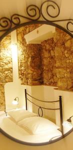 a mirror reflecting a bed in a room with a stone wall at incantevole e storico appartamento in pieno centro in Taormina