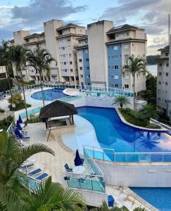 a large swimming pool with blue chairs and buildings at Porto Real Suites Mangaratiba in Mangaratiba