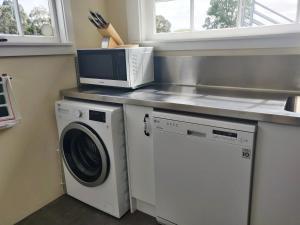 uma cozinha com um micro-ondas e uma máquina de lavar roupa em Bramley's Stables and Accommodation em Rangiora