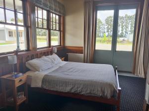 Bramley's Stables and Accommodation في رانجيورا: غرفة نوم مع سرير ونوافذ اثنين وسرير سيد