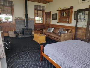 朗伊奥拉Bramley's Stables and Accommodation的一间带床、沙发和壁炉的卧室