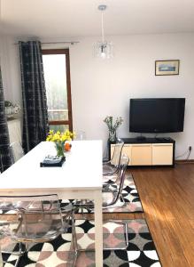 ein Wohnzimmer mit einem weißen Tisch und einem TV in der Unterkunft Apartament z prywatnym tarasem na dachu Ogień 8 Jurata in Jurata