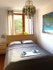 a bedroom with a bed with towels and a chandelier at Apartament z prywatnym tarasem na dachu Ogień 8 Jurata in Jurata