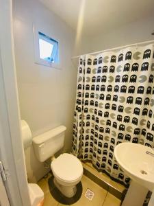 a bathroom with a toilet and a sink and a shower curtain at Hostel Playa Grande Austral in Mar del Plata +40 photos