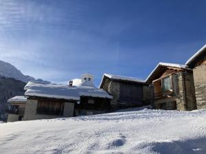 een huis met sneeuw op de grond ervoor bij Gääschi Leis in Vals