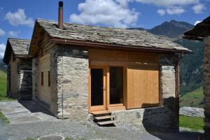 ein kleines Steinhaus mit Holztüren auf einem Berg in der Unterkunft Gääschi Leis in Vals
