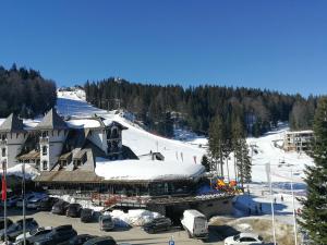 a ski resort with a snow covered building and a parking lot at Snježna Vila in Jahorina