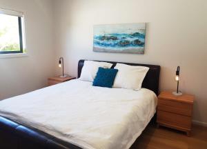 a bedroom with a bed with white sheets and blue pillows at Normanville Getaway in Normanville