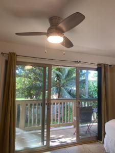 a living room with a ceiling fan and a sliding glass door at Beach Side Studio by Shark's Cove in Haleiwa