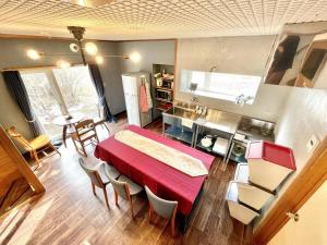 ヴィラYukara緑屋 في Nanae: غرفة معيشة مع طاولة حمراء وكراسي
