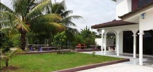 a house with a yard with a palm tree at Sunrise Homestay in Alor Setar
