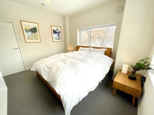 a bedroom with a bed with white sheets and a window at The Bunker at Yunosato in Rankoshi