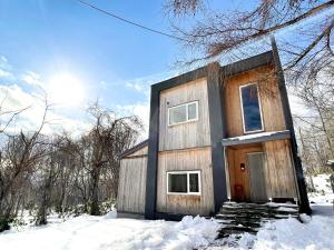 a small house in the snow with the sun behind it at The Bunker at Yunosato in Rankoshi