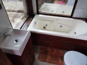 プライア・グランデにあるChalé Espelhado no Itaimbezinhoの浴槽、洗面台、トイレを備えたバスルーム