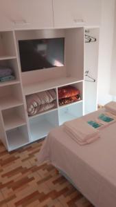 Una habitación blanca con una cama y un televisor. en APART ANTARES, en Dolores 22 fotos más