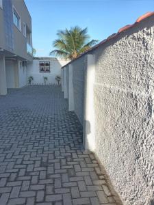 a brick sidewalk next to a wall with a palm tree at Apartamento na Praia de Pontal do Sul- Pontal do Paraná in Pontal do Paraná