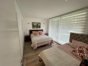 1 dormitorio con 2 camas y una ventana con persianas en DEPARTAMENTOS ESPACIO PUCON, en Pucón