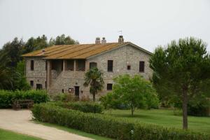 uma antiga casa de pedra com árvores e arbustos à sua frente em Agriturismo Volta Di Sacco em Grosseto