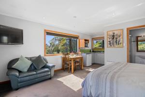 a bedroom with a bed and a couch and a table at Upepo - The Garden Room - Cape Foulwind Studio in Cape Foulwind