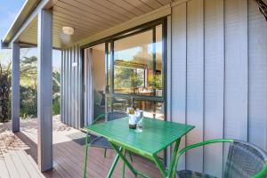 a green table and chairs on a porch at Upepo - The Garden Room - Cape Foulwind Studio in Cape Foulwind