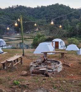 a picnic table and a grill with tents in the background at ข้างเขาแคมป์ Khangkhao Camp in Ban Yang Khun Wang