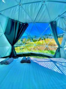 a tent with a bed with a view of a field at ข้างเขาแคมป์ Khangkhao Camp in Ban Yang Khun Wang