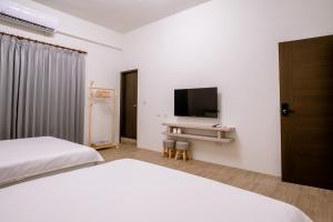 1 Schlafzimmer mit 2 Betten und einem Flachbild-TV in der Unterkunft 澎湖逸軒居民宿 in Huxi