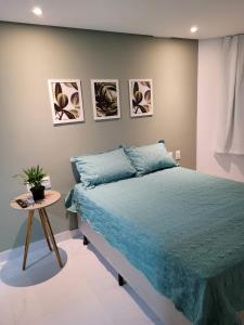 a bedroom with a blue bed and a table at Espetacular Flat em Miramar 2 in João Pessoa
